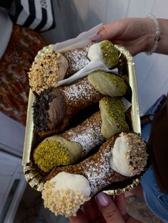 a person is holding up a tray with pastries in it and powdered sugar sprinkled on top