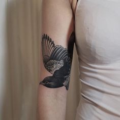 a black and white bird tattoo on the arm