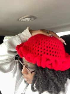 a woman wearing a red crochet hat in the back seat of a car