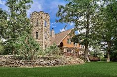 a large stone building sitting in the middle of a lush green field next to trees