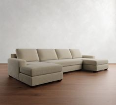 a beige sectional couch sitting on top of a wooden floor next to a white wall