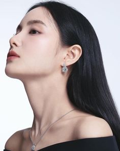 a woman with long black hair wearing an elegant necklace and earrings, looking up at the sky