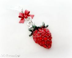 a red strawberry charm on a white background