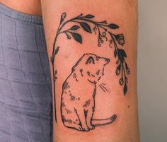 a woman's arm with a cat and leaves tattoo on the left side of her arm