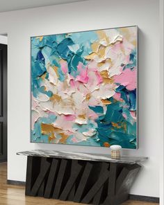 an abstract painting hangs on the wall above a console table