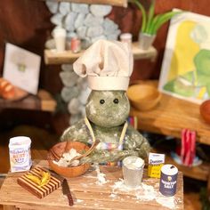 a stuffed animal with a chef's hat sitting on top of a wooden table