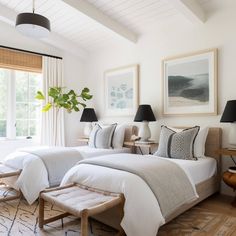 two beds in a bedroom with white linens and pillows on top of each bed