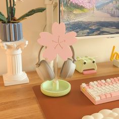 a computer desk with headphones and a pink flower on top of the mouse pad