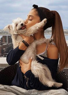 a woman sitting on top of a roof holding a dog