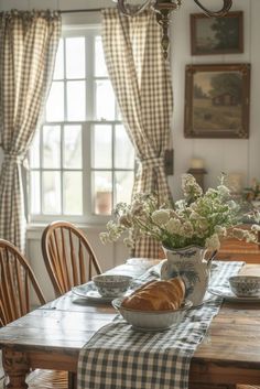 a wooden table topped with plates and bowls filled with food next to a window covered in curtains