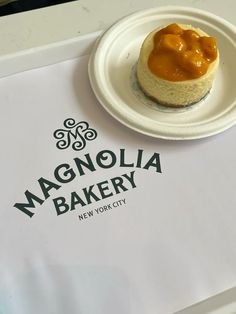 there is a small pastry on a paper plate next to a sign that says magnolia bakery