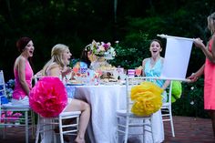 three women sitting at a table laughing and having fun with each other while one woman holds up a piece of paper