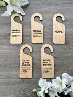 four wooden door hangers with different sayings on them next to flowers and a potted plant