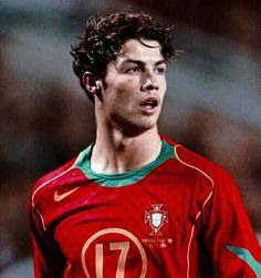 a young man wearing a red and green soccer uniform looking off to the side with his mouth open