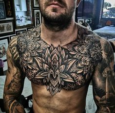 a man with lots of tattoos on his chest and chest is looking at the camera