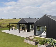 a black house with people sitting on the porch and eating out in the back yard