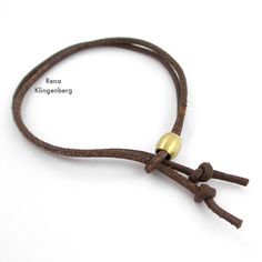 a brown leather cord with two gold beads on the end, and a white background