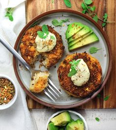 three crab cakes on a plate with avocado slices