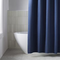 a blue shower curtain in a bathroom next to a bathtub and window with white tiles on the floor