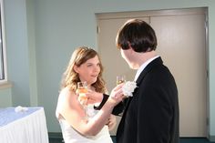 a man and woman standing next to each other holding wine glasses in their hands while looking at each other