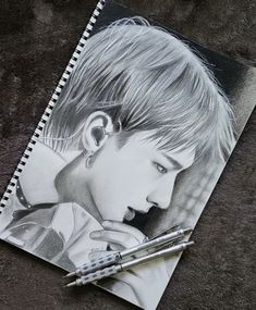 a pencil drawing of a boy with blonde hair and piercings on his ears next to a pen