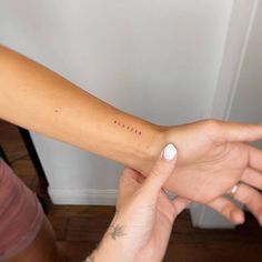 a person with a small tattoo on their arm holding another hand up to the camera