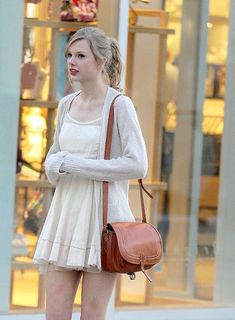 a woman walking down the street carrying a brown purse