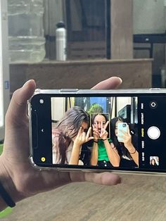 a person holding up a cell phone to take a selfie with two other people in the background