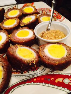 an assortment of food on a plate with a bowl of sauce in the middle and other foods