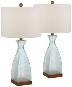 two blue glass lamps with white shades on them