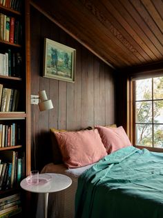 a bed in a room with bookshelves on the wall and a table next to it