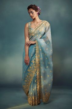 a woman in a blue and gold sari with flowers on her head, posing for the camera