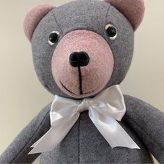 a gray teddy bear with a white bow around it's neck and eyes,