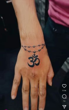 a person's hand with a small tattoo on the wrist and an omen symbol