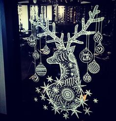 a lighted reindeer with ornaments hanging from it's antlers and stars on the window