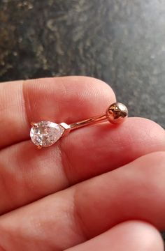 a person is holding a tiny gold nose ring with a white diamond in the middle