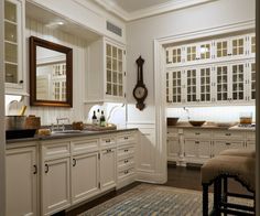 a large kitchen with white cabinets and black counter tops, along with a blue area rug on the floor