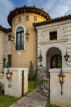 a large house with an iron gate and light fixtures on the front entrance to it