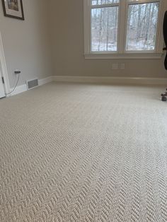 an empty living room with carpeted floors and two windows