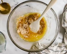 a bowl filled with food next to two spoons on top of a marble counter