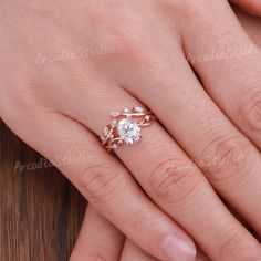 a woman's hand with a diamond ring on top of her finger and the other hand holding an engagement ring