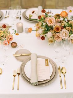 a table set with place settings and flowers