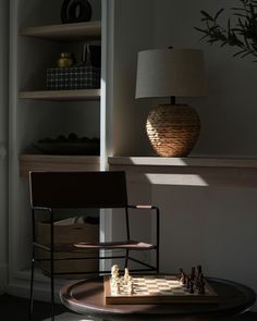 a chess board sitting on top of a table next to a lamp and book shelf