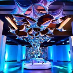 a room with blue lighting and white couches in the center is lit up by colorful lights