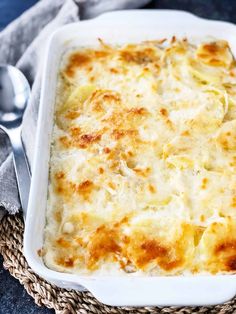 a white casserole dish with cheese and potatoes