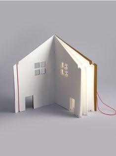 an open book that is shaped like a house with two windows and a red cord