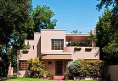 a pink house with trees and bushes around it