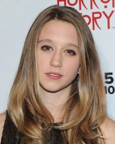 a woman with long hair standing in front of a sign