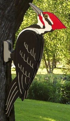 a red and white bird is perched on the side of a tree in a park