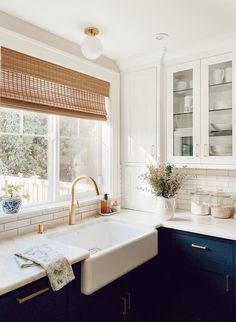 a kitchen with blue cabinets and white counter tops is pictured in this image, there are dishes on the window sill